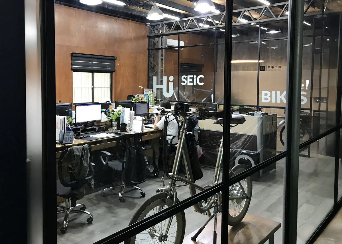 SEic 品牌早期的實體門市外觀。純白色的兩層樓建築，圓形招牌印有 SEic 字樣與「單車工房」字眼。二樓陽台擺放著客製化單速車，整體風格簡約清新，展現品牌早期扎根於生活美學的概念據點。