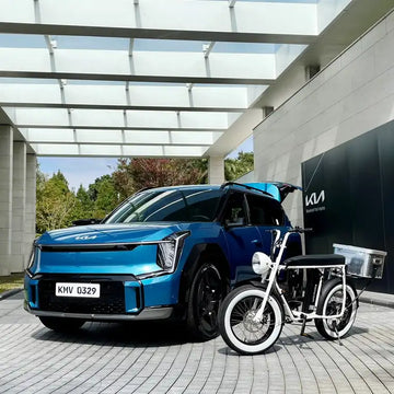 藍色 Kia 電動休旅車與白色電輔車並排停在建築前