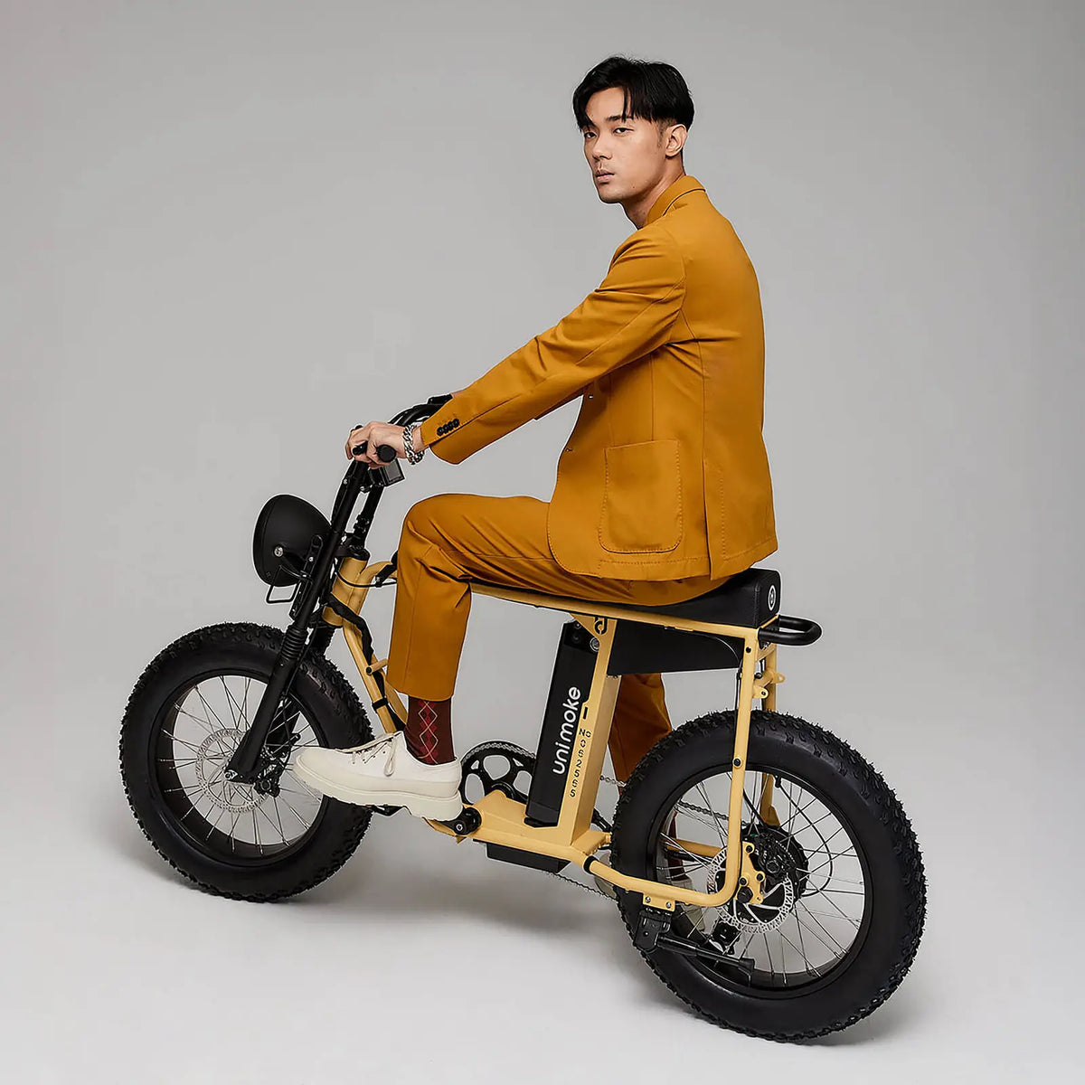 身穿西裝的男人騎著 Unimoke MK 沙漠黃，整體簡潔俐落