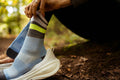 一位登山者穿著一雙 INCYLENCE Merino Strive 羊毛運動機能襪淺藍草以及白色運動鞋