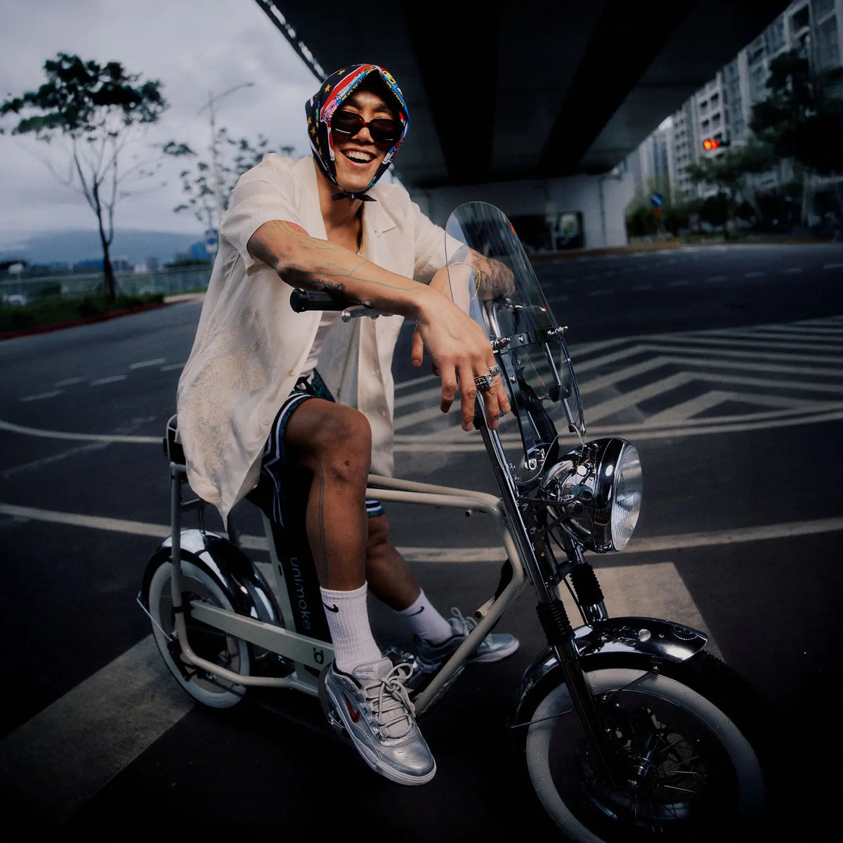一名男子在路上騎乘 minibike ，對著鏡頭露出笑容